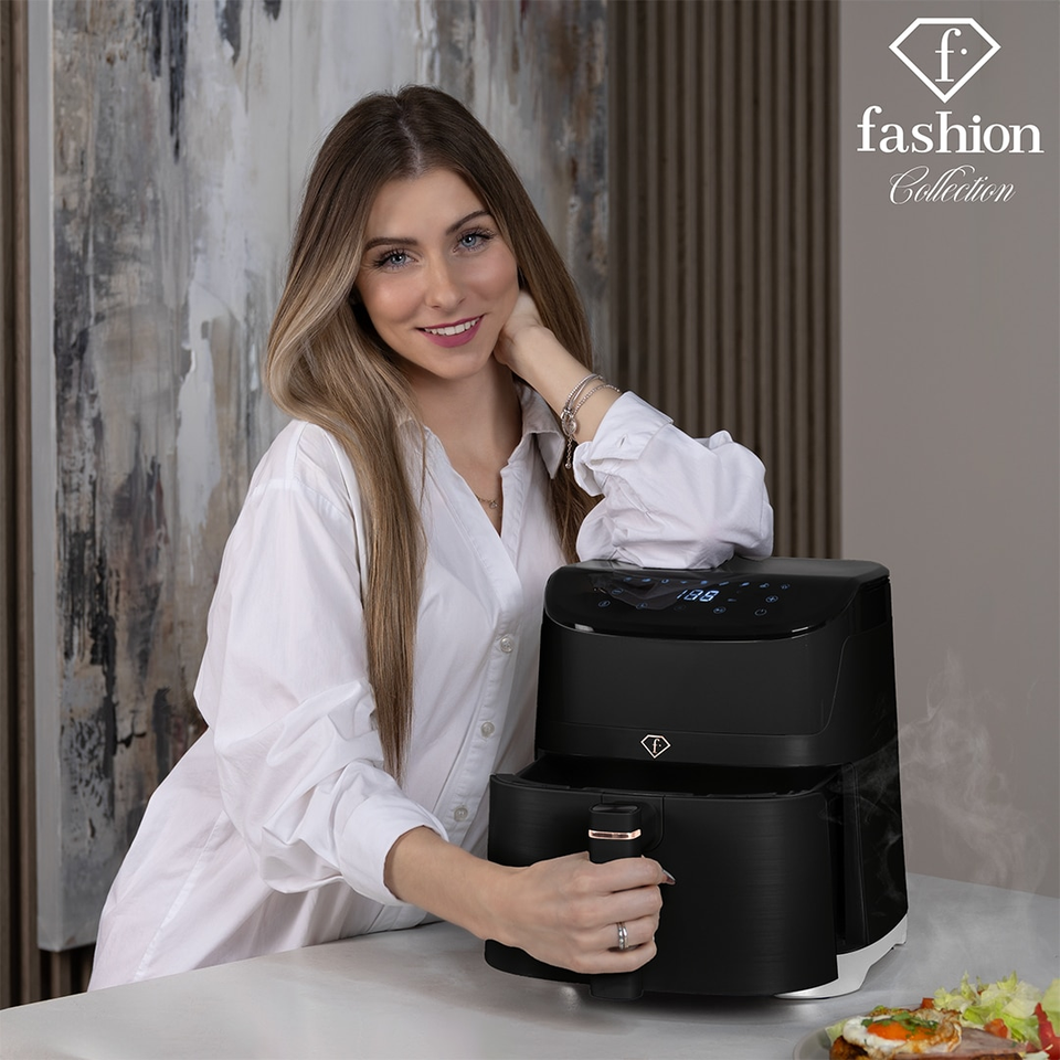 Woman in a white shirt smiles at the camera while using a black air fryer; 'fashion Collection' logo in the top-right corner.
