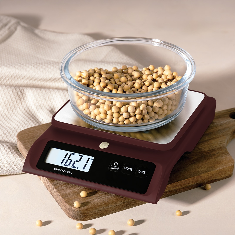 Digital kitchen scale with a glass bowl full of small yellow soybeans, displaying 162.1 g on the screen on a wooden board.